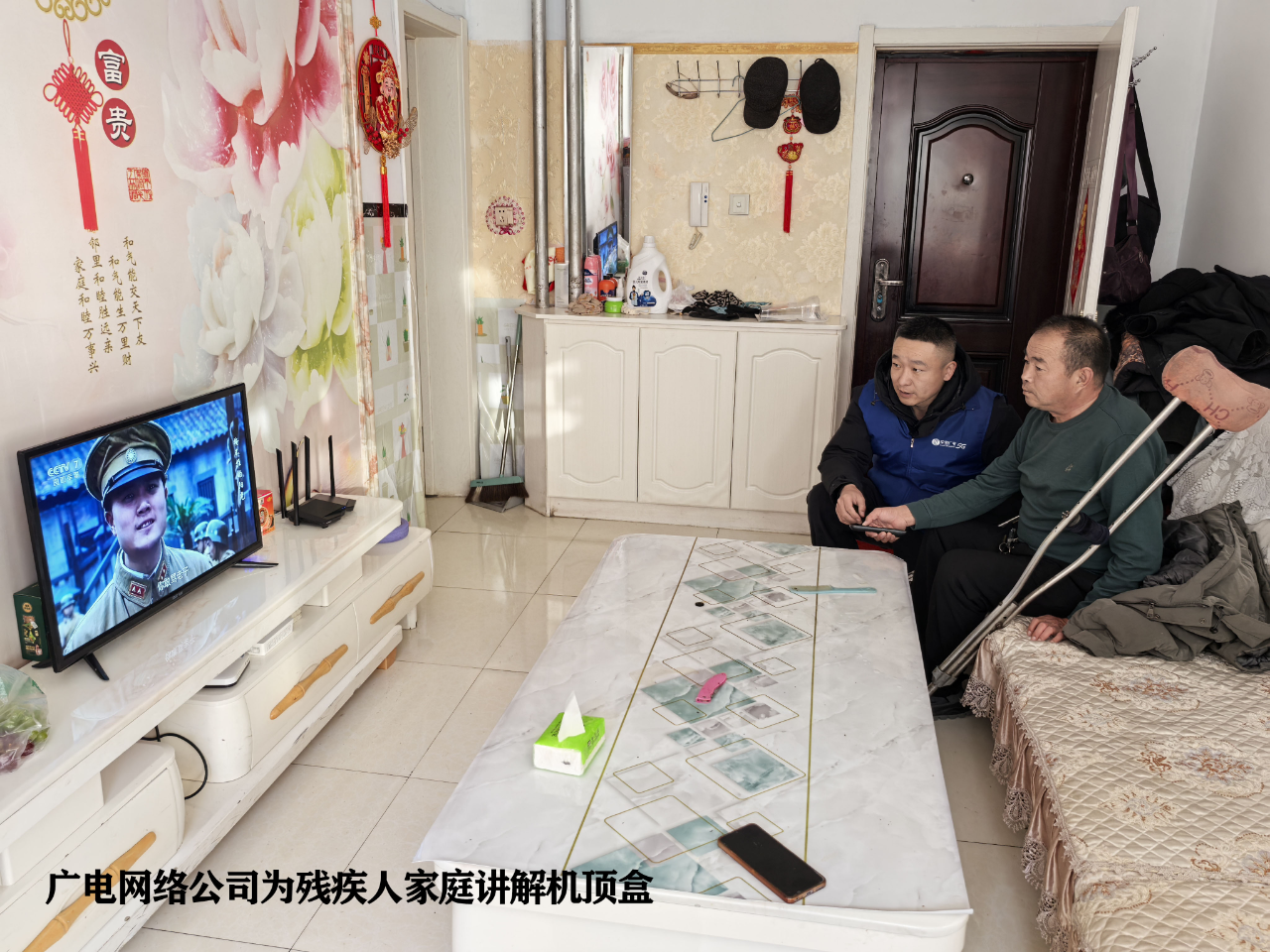 图为广电网络公司为残疾人家庭讲解机顶盒